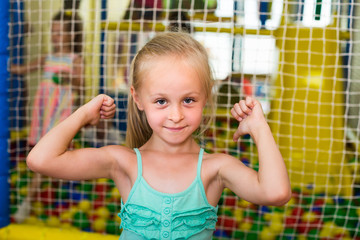 girl in bright dress looking happy and standing on indoor playground