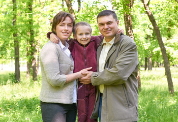 happy family with child in summer park, sunlight, green grass and trees