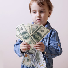 Money is the best motivation. A child holding dollars banknotes. (Development, business success, freedom, career, power concept)
