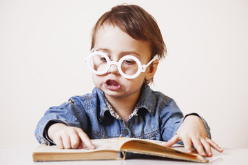 Expressive girl child reading a magic book. (Education, knowledge, wisdom, magic, childhood concept)