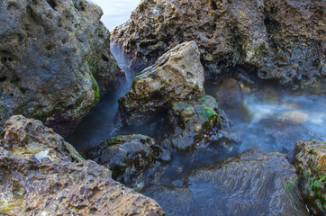 Sea wave on a background of stones closeup on a long exposure