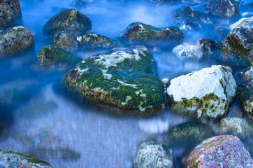 Sea wave on a background of stones in the foreground on a long exposure.