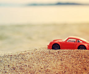 Fototapeta na wymiar Children's red machine on sea sand against the background of the sea 