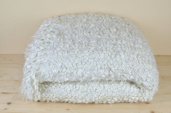 White soft woolen blanket with cozy look on wooden shelf