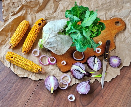 Cabbage, onion and corn on a cutting board.