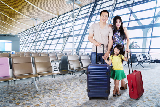 Asian Family With Suitcases At Airport
