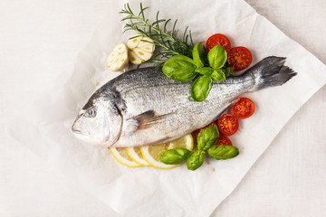 Raw fish cooking and ingredients. Dorado, lemon, herbs and spices. Top view on stone table