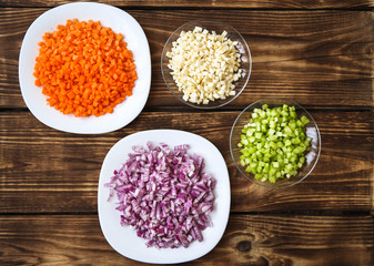 Chopped vegetables in white bowls on wood background