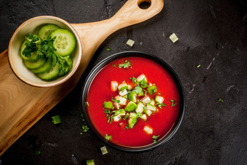 Summer diet cold soup gazpacho, tomato, cucumber and greens on a black concrete stone table copy space top view