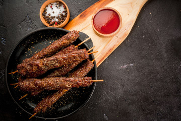 Shish kebab on a stick, from ground beef meat. Lula kebab, traditional Caucasian dish. On the black...