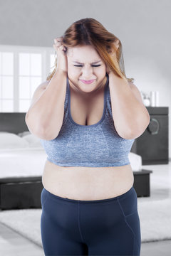 Depressed overweight woman in bedroom