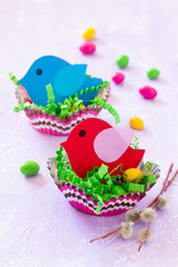 Easter decorations children's table. Easter table decoration nest with baby bird paper and candy, painted quail eggs. Copy space.