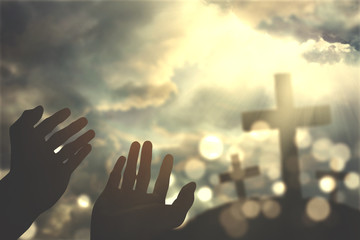 Hands praying with cross on sky