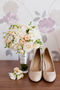 Bride`s wedding accessories: wedding shoes, rings and bouquet or boutonniere with pink and white flowers 