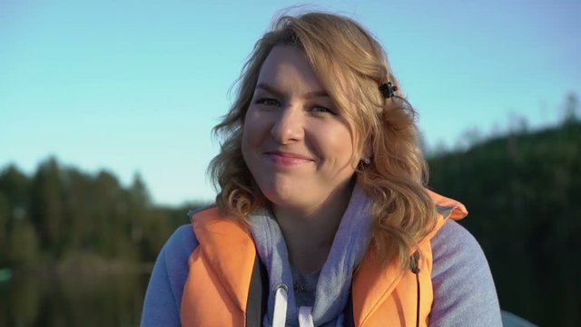 Young blonde woman on a boat in life jacket at the evening