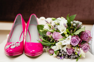 Obraz na płótnie Canvas Bride`s wedding accessories: wedding shoes, rings and bouquet or boutonniere with pink and white flowers 