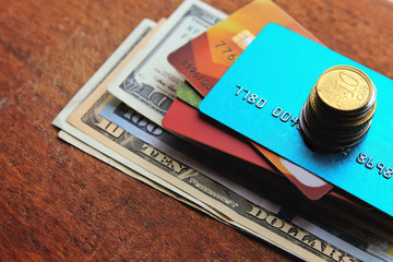 Stack of credit cards with american dollars and coins on a wooden background, close-up view.
