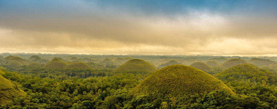 Scenic view of the UNESCO site of Chocolate Hills in Bohol, Philippines, with clouds and sun