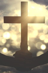 Human hands hold a crucifix symbol
