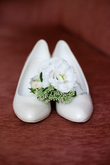 Bride`s wedding accessories: wedding shoes, rings and bouquet or boutonniere with white flowers 