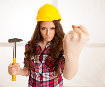 angry woman holds hammer and shows fist