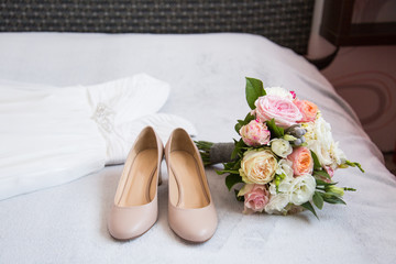 Bride`s wedding accessories: wedding shoes, rings and bouquet or boutonniere with pink and white flowers 