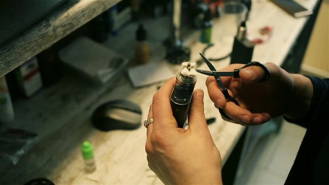 Male hands cut cotton wool for the electronic cigarette. After-sales service of the e-cigarette. ENDS.