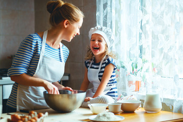 happy family in kitchen. mother and child preparing dough, bake cookies