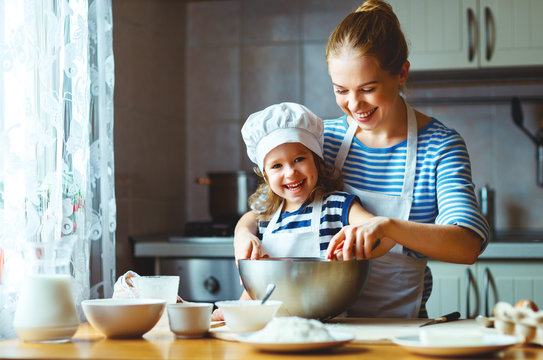 happy family in kitchen. mother and child preparing dough, bake cookies