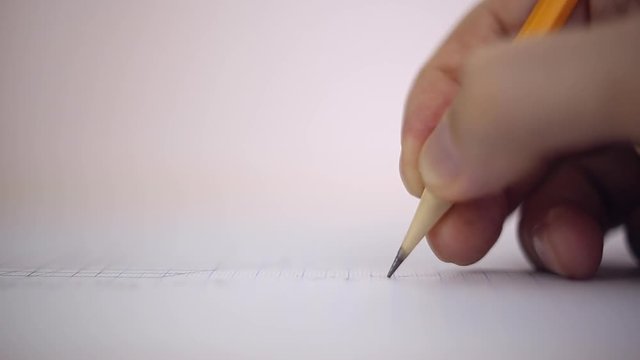 Draftsman draws a pencil on a sheet of paper, macro
