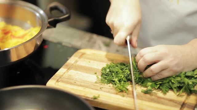 Close-up of chef hands cooking and cut dill in restaurant kitchen
