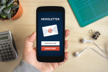 Hand holding smart phone with subscribe newsletter concept on screen. All screen content is...