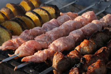 raw and roasted meat with spices and potatoes on skewers