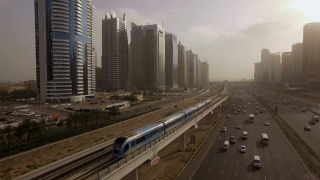 the train goes over the viaduct, along the highway among the skyscrapers in Dubai, UAE