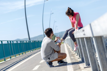 Young man helps a woman after an injury from a running.