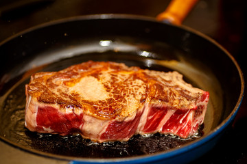Raw beef loin on the bone (marble), fried in a skillet.