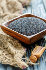Poppy seeds in a square wooden bowl.