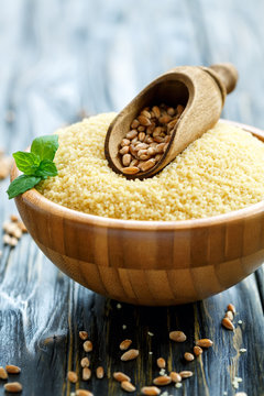 Scoop with wheat in a wooden bowl with couscous.