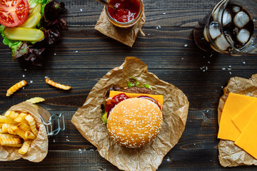 Fresh tasty burgers with french fries, sauce and drink on the wooden table top view