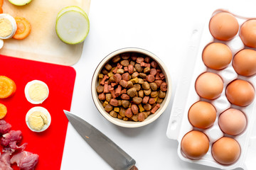 food for pets with meat and eggs on kitchen background top view