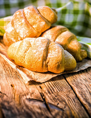 Tasty buttery croissants on old wooden table.