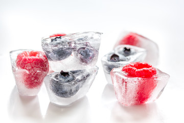 Ice cubes with frozen berries on white background