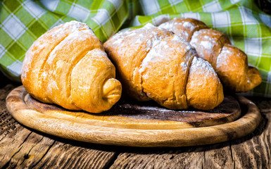 Tasty buttery croissants on old wooden table.