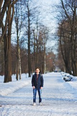 Young smiling man walks through the snowy Park on a clear winter day