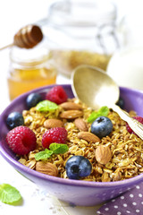 Homemade granola with fresh berry for a breakfast in a purple bowl.