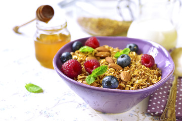 Homemade granola with fresh berry for a breakfast in a purple bowl.