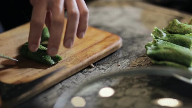 Chef cutting hot cooked spinach green pancakes on a board