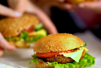New cooking of hamburger fast food with ham on wooden board . Group of hamburger. Human hand holding cheeseburger. Sharpness in front of sandwich.