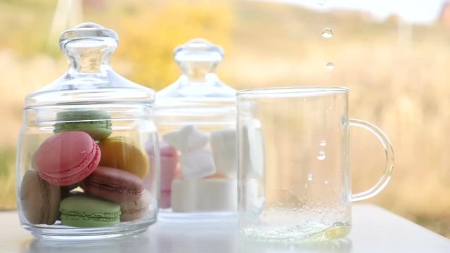 Cup of mint tea with macarons and marshmallows. Beautiful sunny day in spring. Green and yellow background. French bakery with hot tea. Tasty breakfast, spring mood.