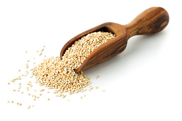 Raw, whole, unprocessed quinoa seed in wooden scoop on white